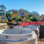 Construction site scene with a digger and a house representing Glanville Trenchless expertise in civil engineering.